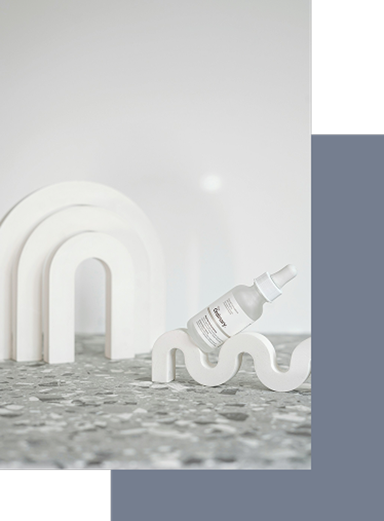 くすんだホワイトを背景に、様々な形状の物体があり、そこにエンビロンのスキンケア製品が配置された静物写真