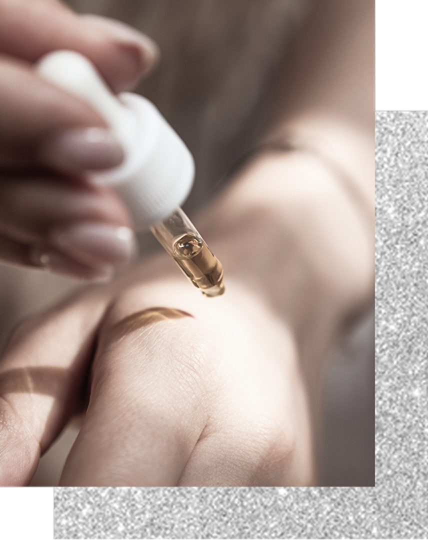 清潔感のある手元で、ガラス製スポイトを使いスキンケア用オイルを肌に塗布する様子