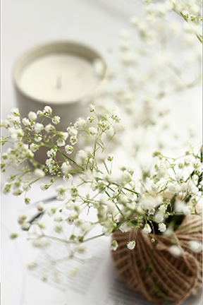 手前にかすみ草の花束、奥に白いキャンドルがぼんやりと写る、落ち着いた雰囲気のインテリア